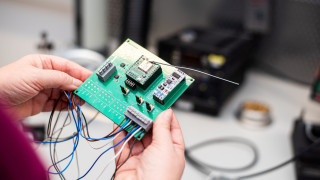 Ihmisen kädet, jotka pitelevät piirilevyä.